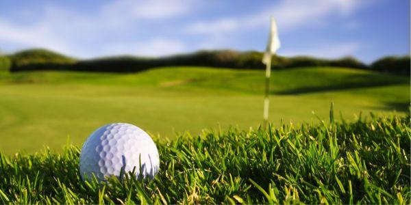 Golf ball on a green putting surface with a flag in the background.